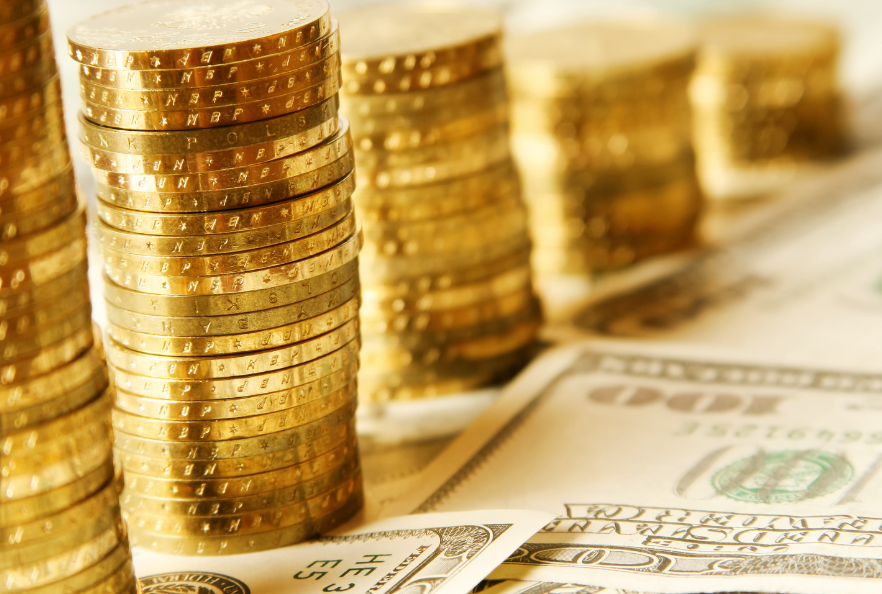 Image of $100 bills on a surface surrounded by piles of gold coins.