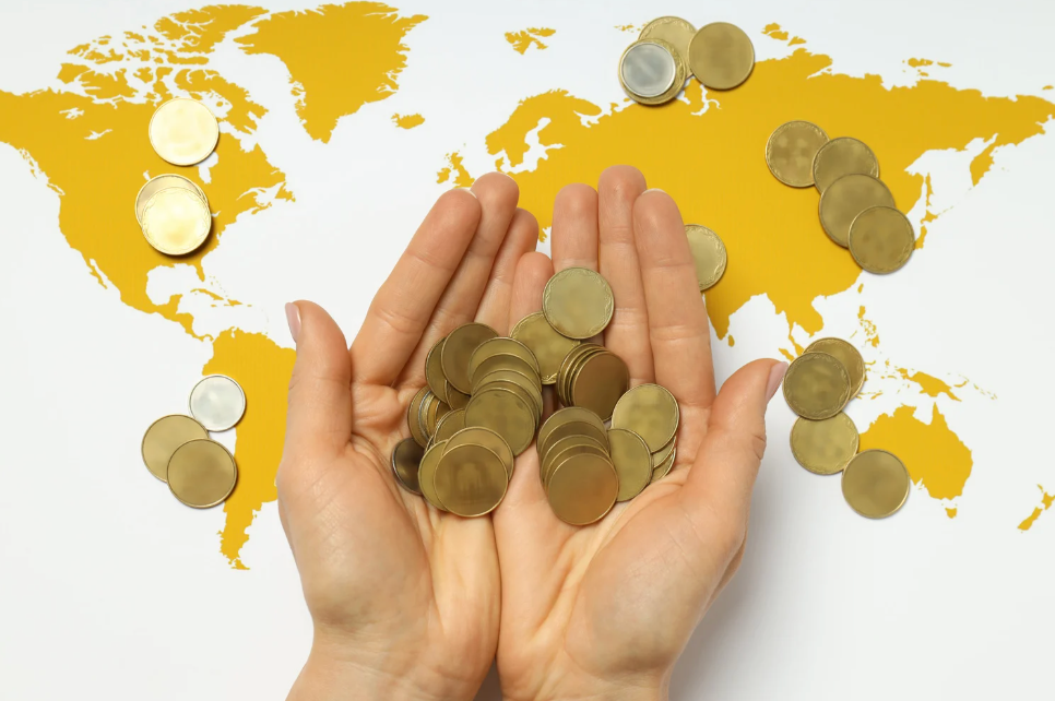 Image of a map of the world with hands holding gold coins