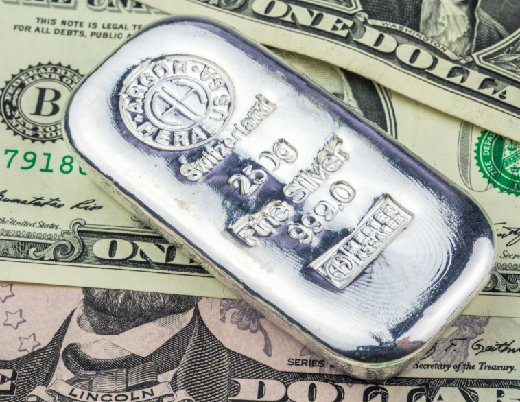 Close up of a silver bar laying on cash